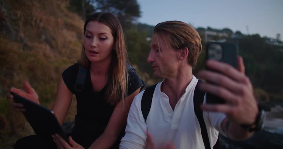 A man and woman talking on a phone and using a tablet