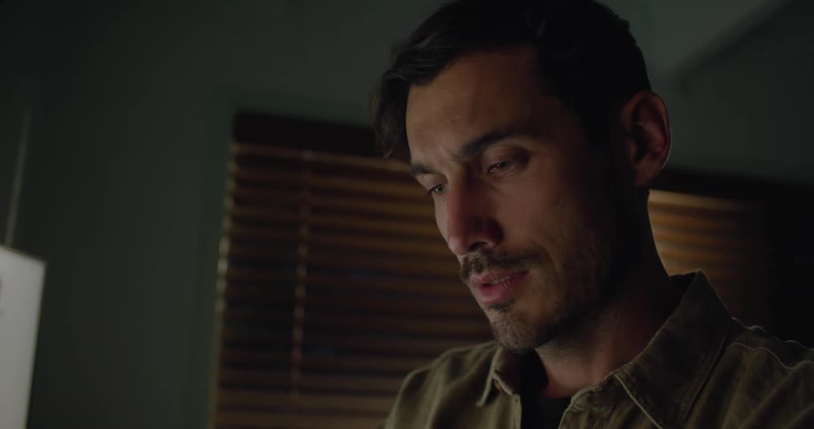 A man in a room looking at a map on a computer screen with a wall and window in the background