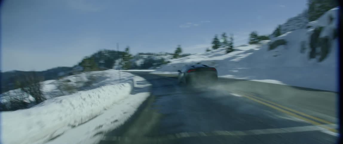 A car drives through a snow-covered forest