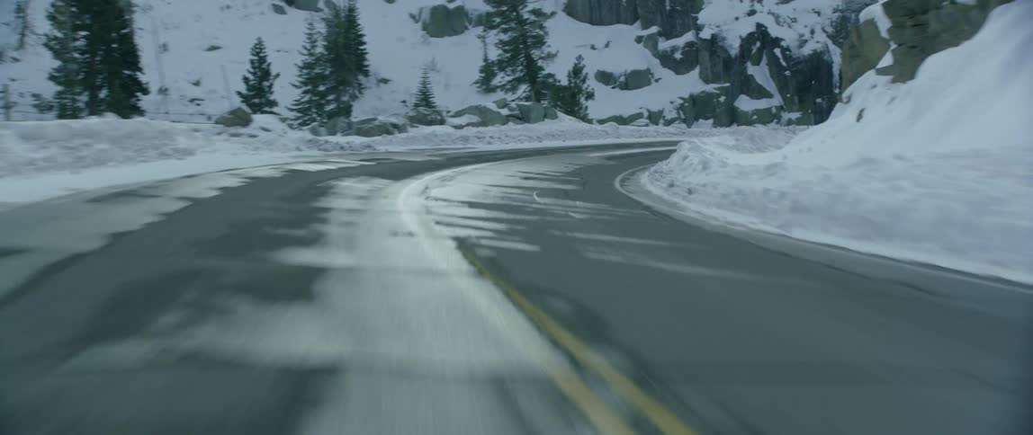 Moving and turning down a twisted road surrounded by snow