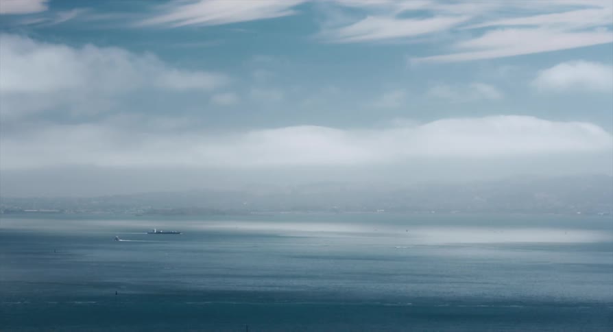 Small boat and large ship pass each other leaving wakes as fog obscures shore