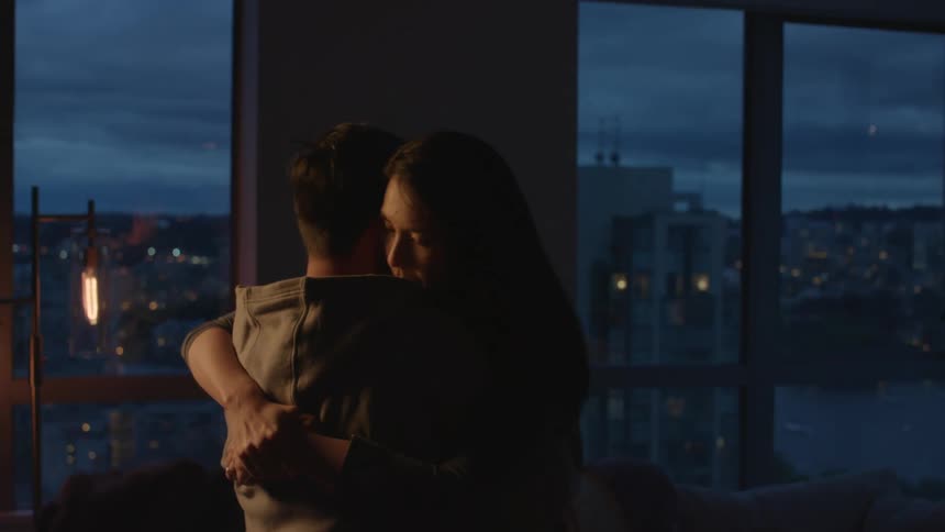 A male and female are in a dark room hugging and dancing