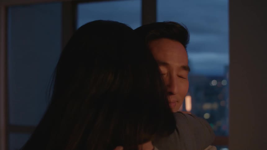 Young couple hug and kiss while slowly dancing at home