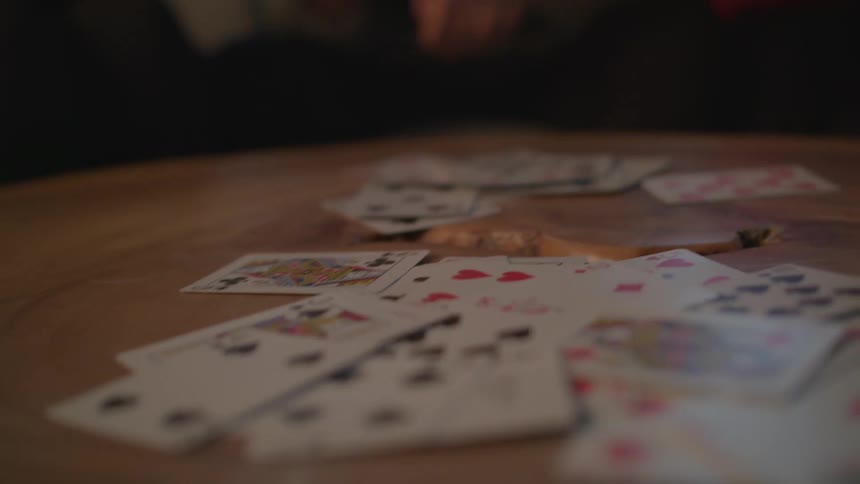 A group of people are throwing cards down on atable as they play a card game