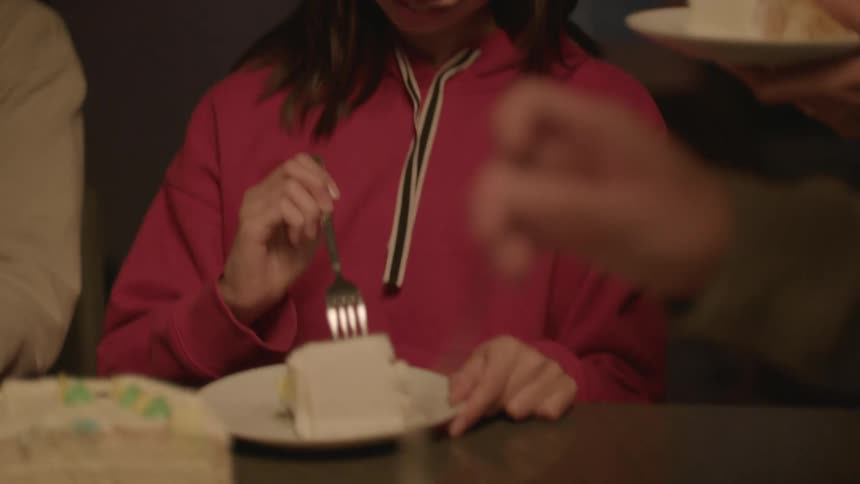 Family eating cake at the table in the apartment kitchen at night