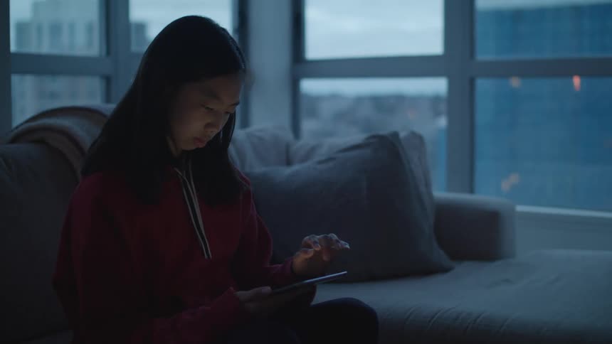 Girl browsing on her smartphone while sitting in the couch at home