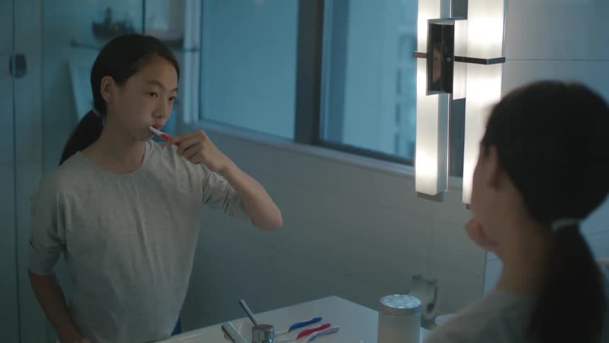 A woman is brushing her teeth in a bathroom
