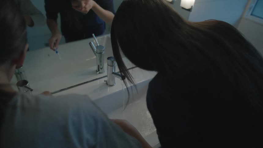 Two females in a bathroom brushing their teeth