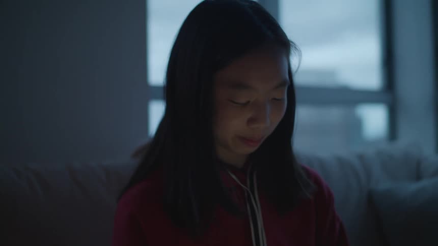 Teenage girl with red sweater and straight hair swipes up and down on tablet screen