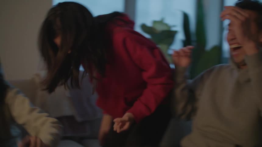 A child celebrates winning a card game while playing with family in their apartment at dusk