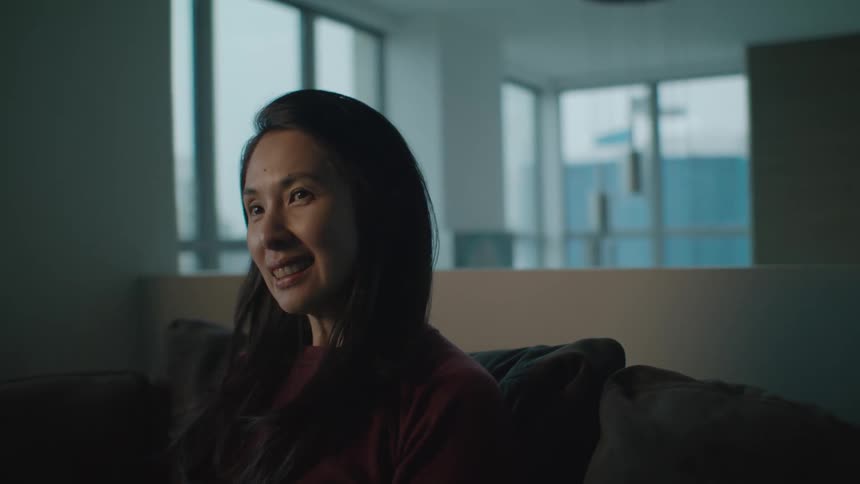A woman smiles as she sits on a couch