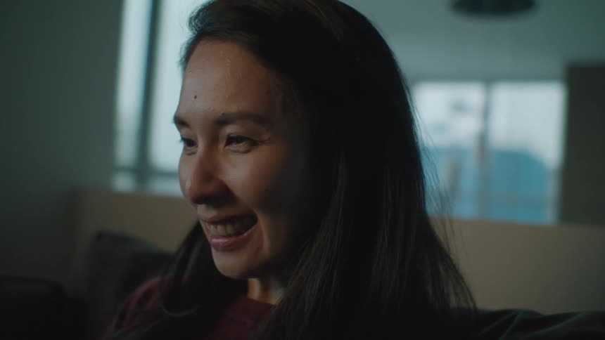 An asian female is sitting in a room smiling laughing and talking