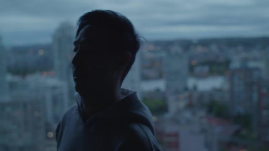 Man standing near a windown in an apartment ends a call on a smartphone