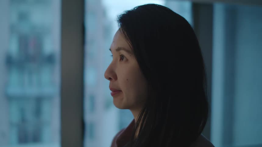 A woman looks upset as she looks out a window then she spins around and speaks