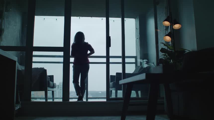 A woman is looking out over her balcony