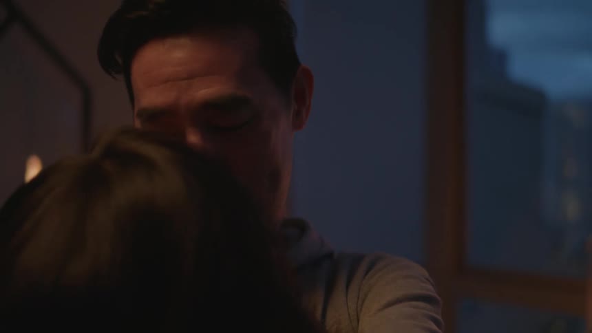 Young couple hug and kiss on the living room of an apartment at evening
