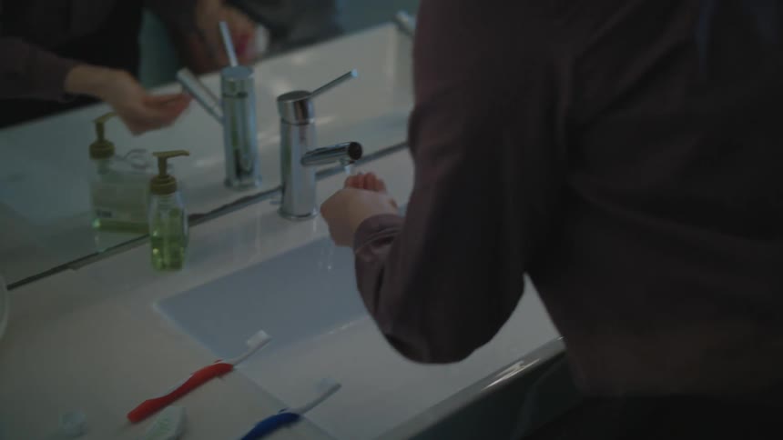 A man and woman are in a bathroom brushing their teeth