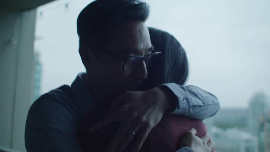 Young happy couple hug each other near a window on an apartment
