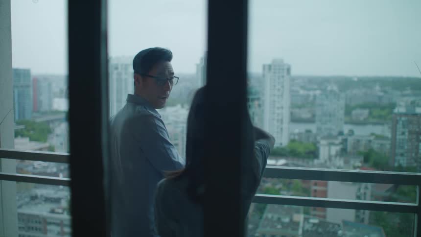 Man standing on the apartment balcony looking at the city greets his daughter
