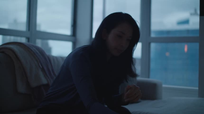 Young woman ends a call on her smartphone while sitting on the living room at home