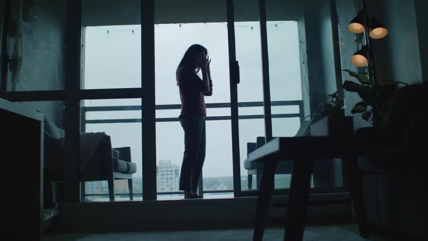 Sad woman crying on the balcony of an apartment