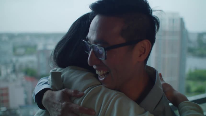 A man and a woman smile and hug one another