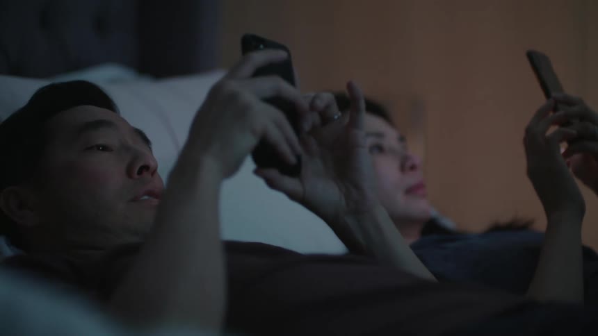 Young couple checking their smartphones togheter in bed