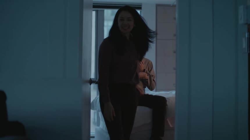 Man sitting on the bed dressing up while his wife kisses him walking out of the bedroom