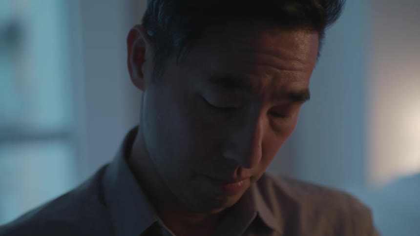 A man in a room staring with a wall and window in the background