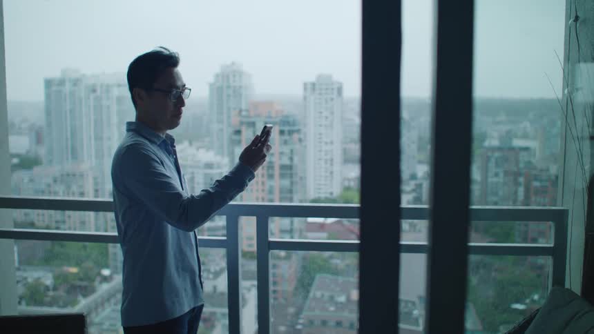 A man answers his phone on the balcony