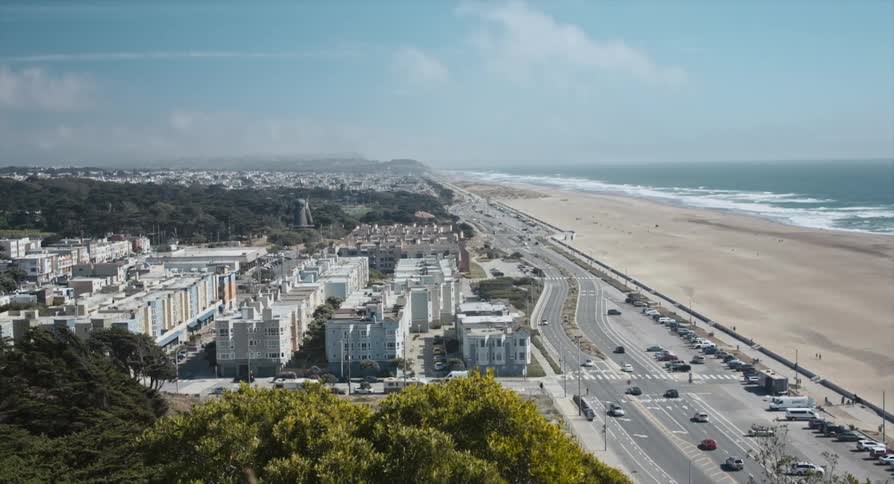 Traffic flows along road between beach and city buildings