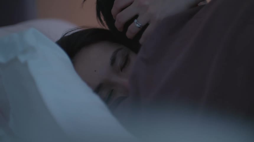 Wife and husband hold each other on bed consoling one another in bedroom