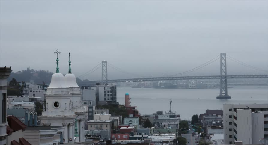 A city with buildings and roads with a bridge a river the sky and clouds in the background