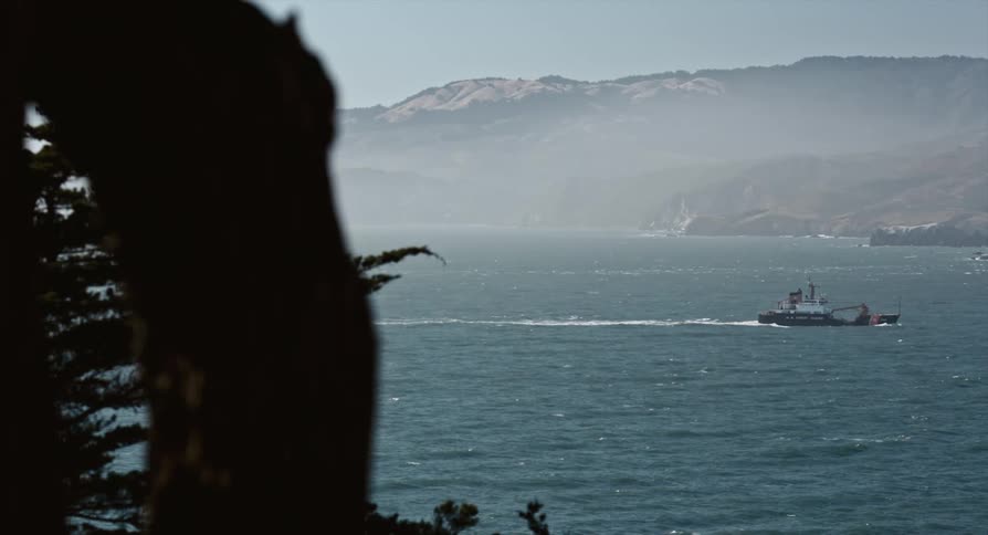 Boat sailing on the ocean near the mist covered mountains