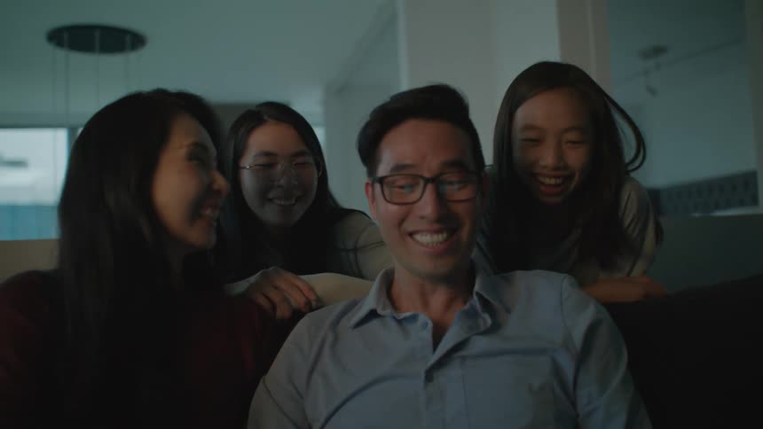Happy family sitting on a couch at home looking at a laptop