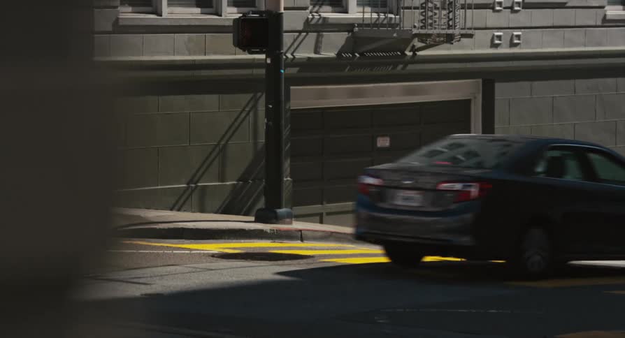 A road with vehicles and a traffic light with a wall and garage door in the background