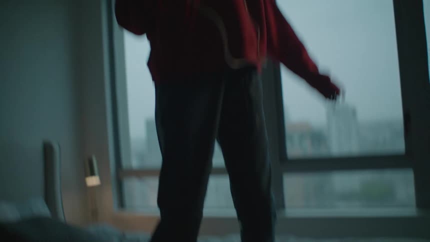A girl is dancing on her bed listening to music