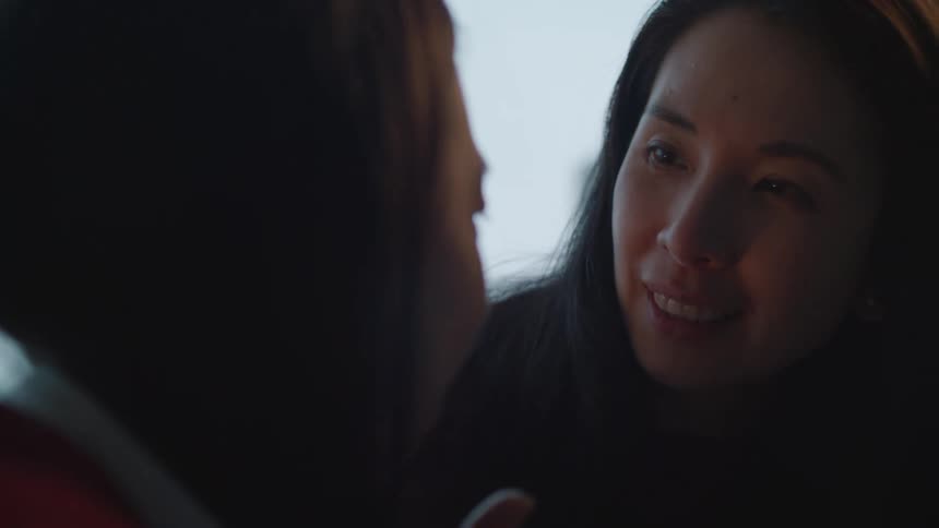 Two women smile and embrace as one kisses the other on the forehead