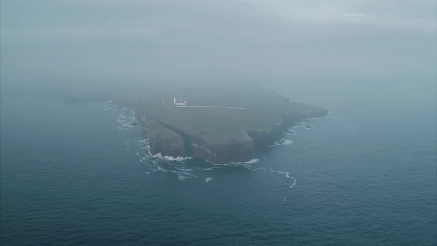 A lighthouse sits on a small rocky island in the middle of the sea