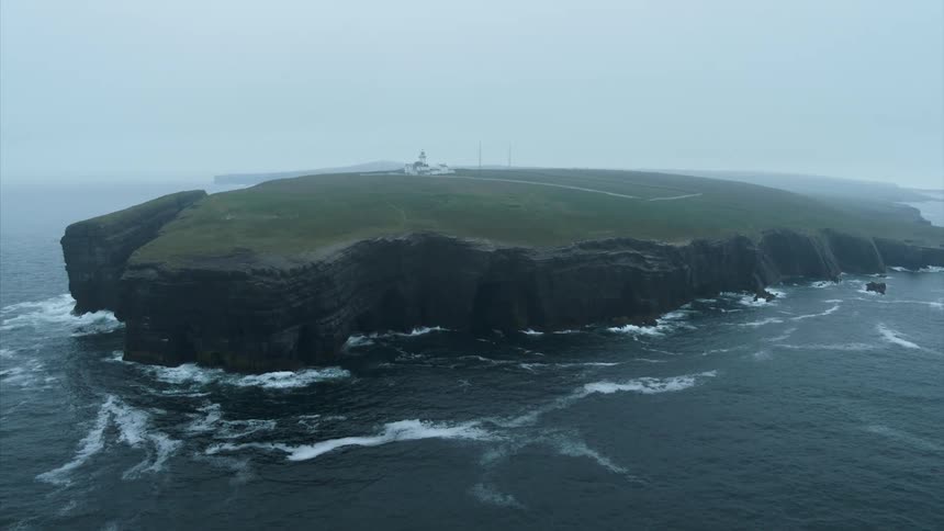 A lighthouse sits on a cliff surrounded by crashing ocean waves