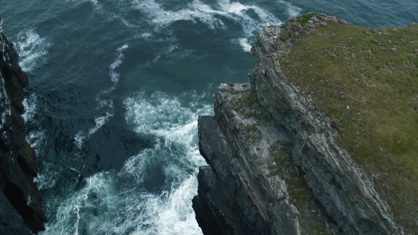Grass covered cliffs drop straight down into the ocean