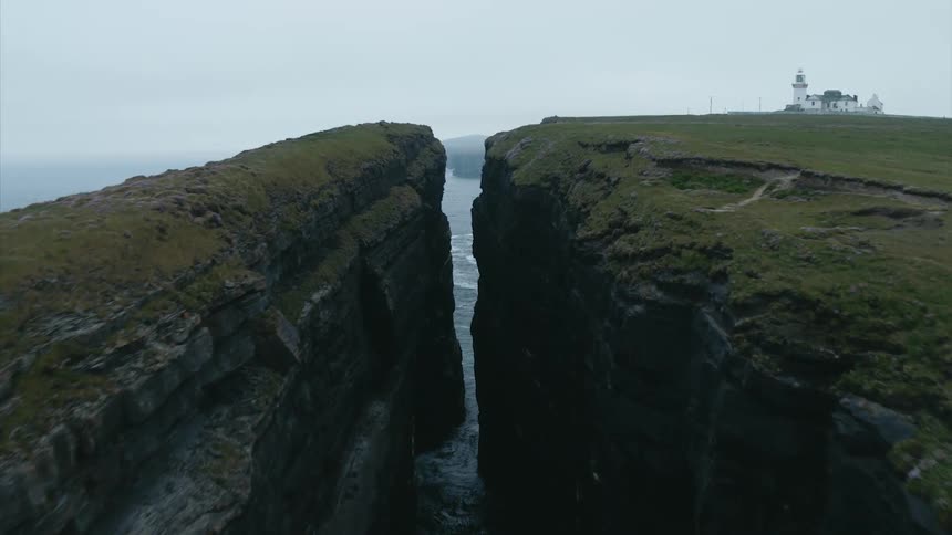 Flying between rocky cliffs over the crashing ocean waves