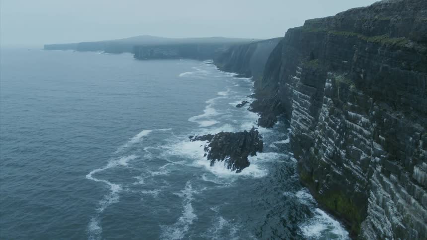 A sheer rocky coastline on a foggy morning