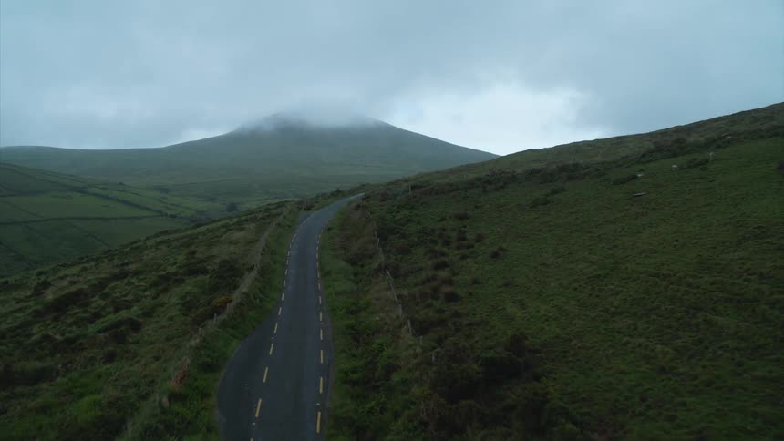 A road runs through grasslands and hilly terrain