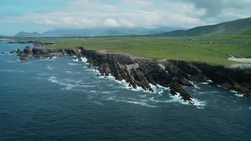 A small village sits back some distance from a rocky coastline