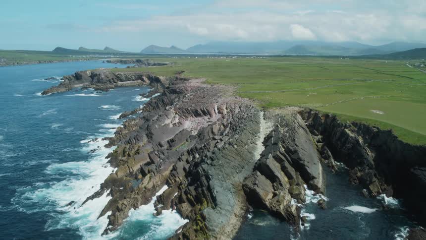Grassy fields lie above a rocky shoreline