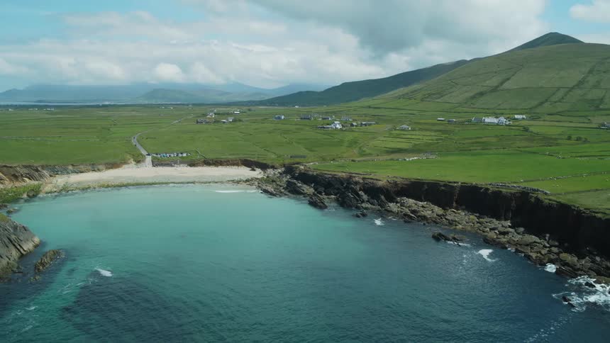 A coastal village with rolling hills and jagged seaside cliffs