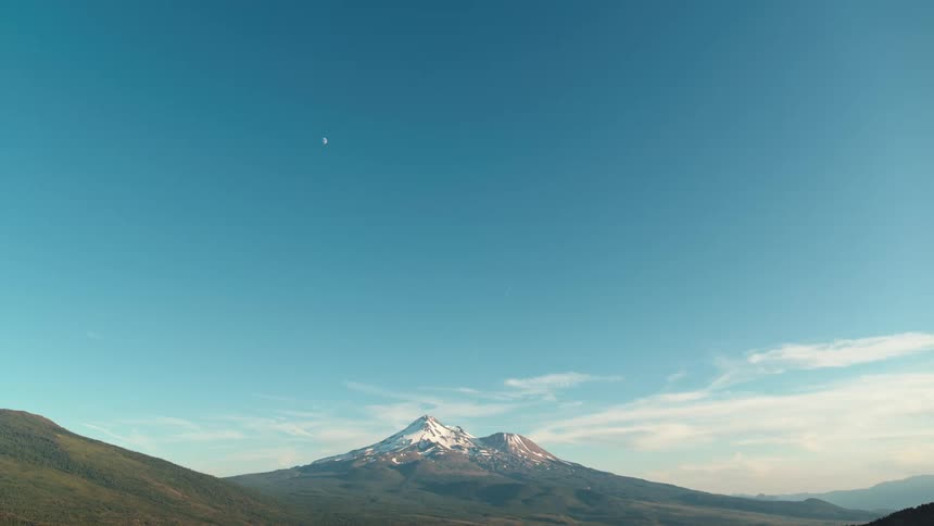 Snowy mountain against the blue sky and small moon