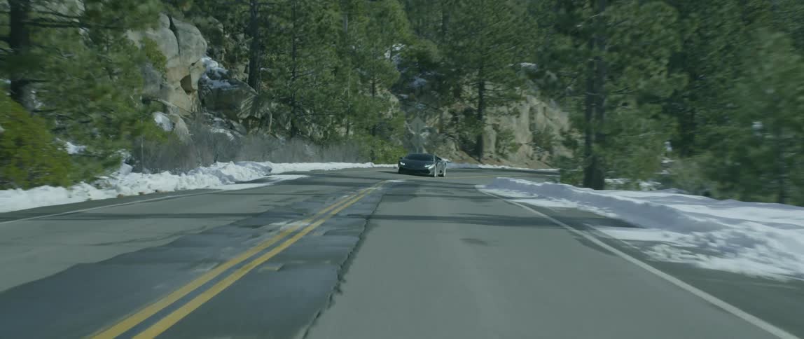 A car passes in the opposite lane near a cliff
