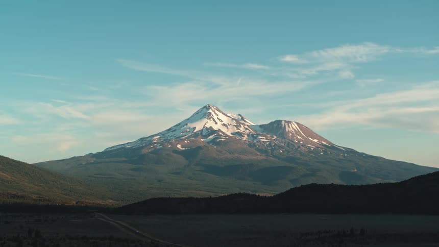 A landscape with a road with a mountain range the sky and clouds in the background
